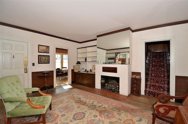 living room with a fireplace, hardwood / wood-style flooring, built in features, and crown molding