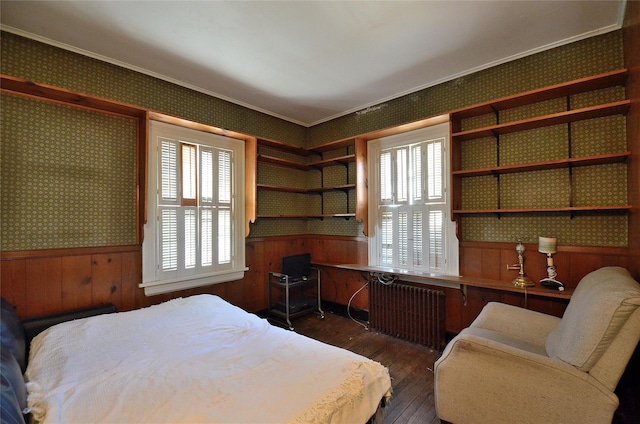 bedroom featuring dark hardwood / wood-style floors, wood walls, crown molding, and radiator