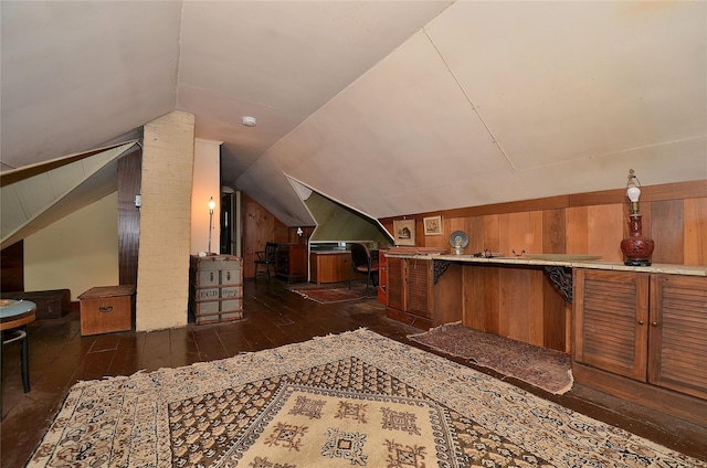 additional living space featuring lofted ceiling, dark wood-type flooring, and wood walls