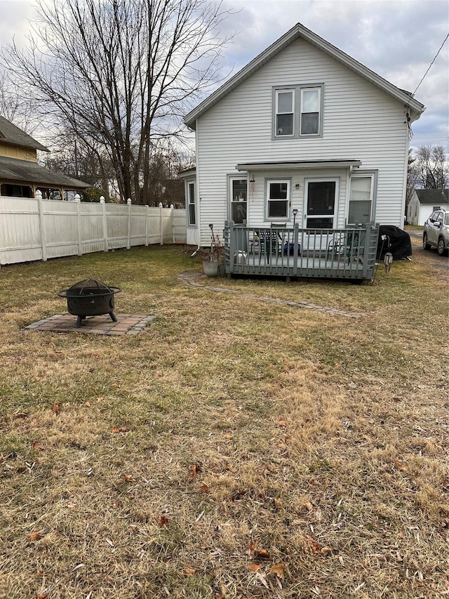 rear view of house featuring a lawn, a wooden deck, and an outdoor fire pit