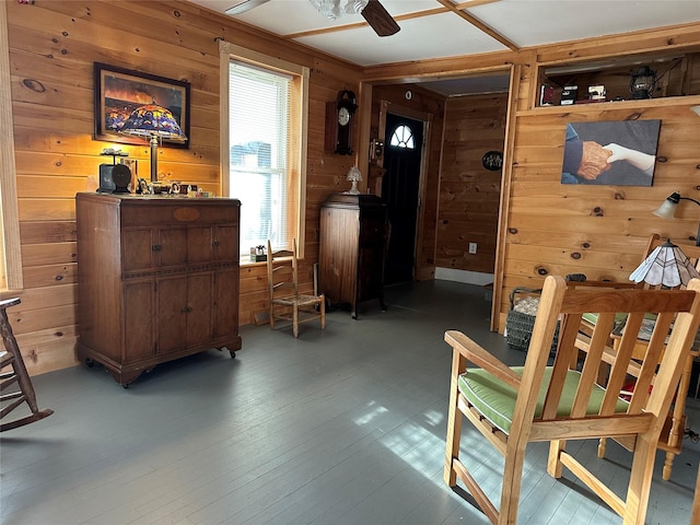 sitting room featuring hardwood / wood-style floors, ceiling fan, and wood walls