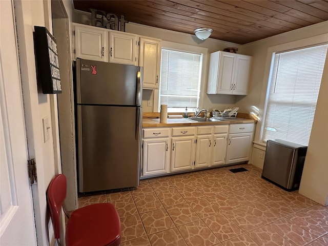 kitchen with white cabinetry, stainless steel fridge, sink, and wooden ceiling