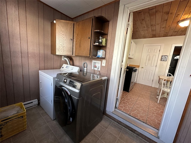 laundry area featuring washer and dryer, a baseboard radiator, cabinets, and wood walls