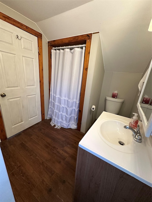 bathroom featuring toilet, wood-type flooring, lofted ceiling, and vanity