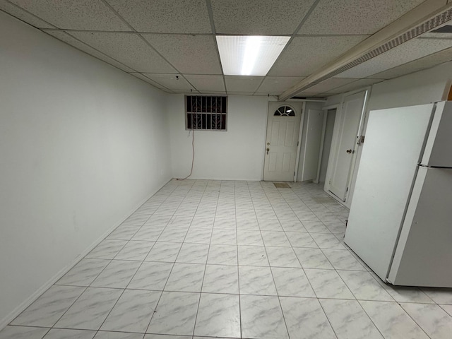 basement featuring white fridge and a paneled ceiling