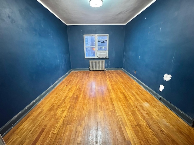 unfurnished room with ornamental molding, hardwood / wood-style floors, and radiator heating unit