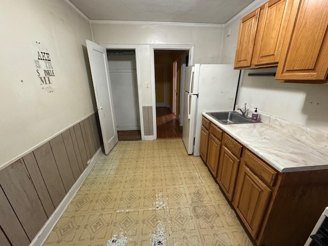 kitchen with wooden walls, sink, and white refrigerator