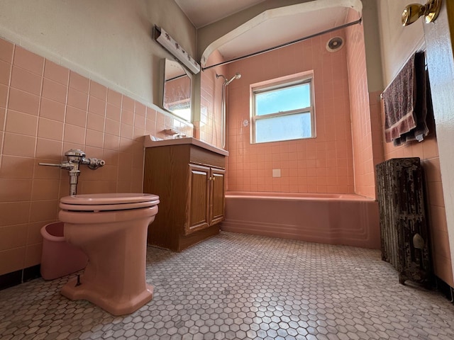 full bathroom featuring toilet, vanity, tile walls, tile patterned floors, and tiled shower / bath combo