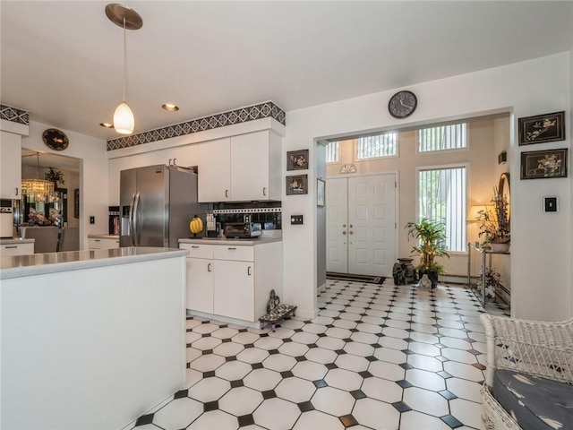 kitchen featuring stainless steel fridge, backsplash, white cabinetry, and pendant lighting