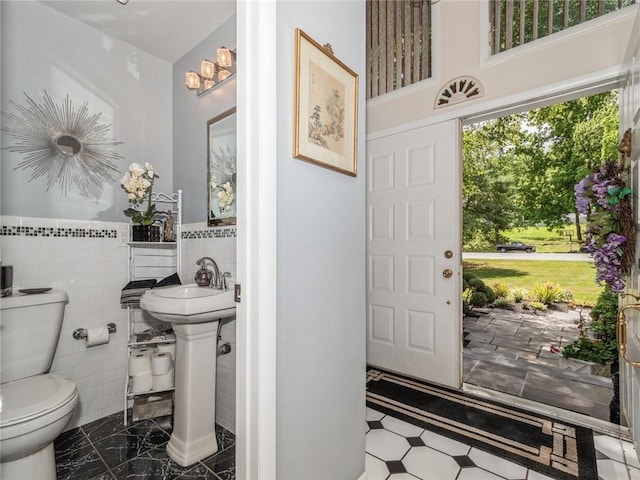 bathroom featuring toilet and tile walls