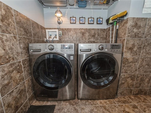 washroom featuring tile walls and washing machine and clothes dryer