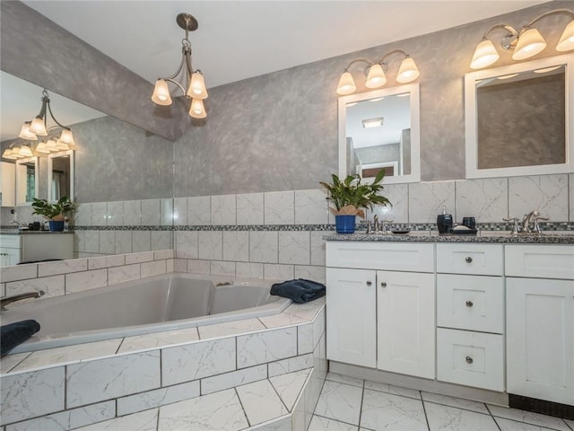 bathroom featuring vanity, tiled bath, and a notable chandelier