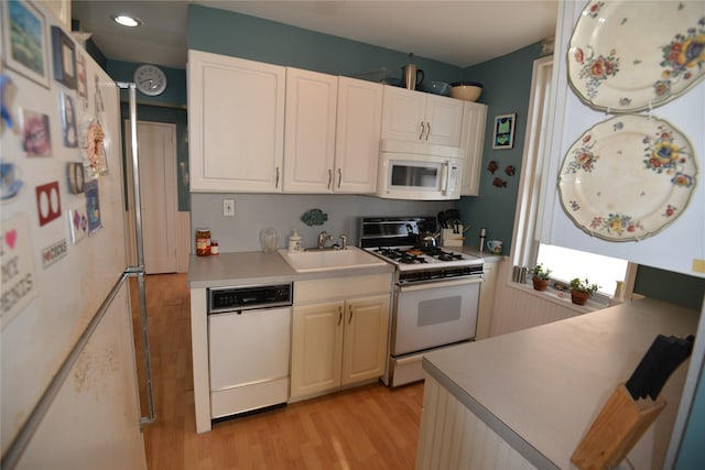 kitchen featuring white cabinetry, sink, white appliances, and light wood-type flooring