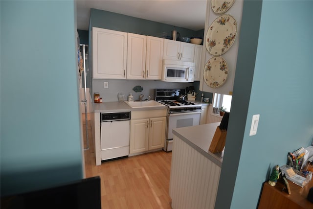 kitchen featuring white cabinetry, white appliances, sink, and light hardwood / wood-style flooring