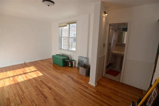 interior space featuring sink, wood-type flooring, and radiator heating unit