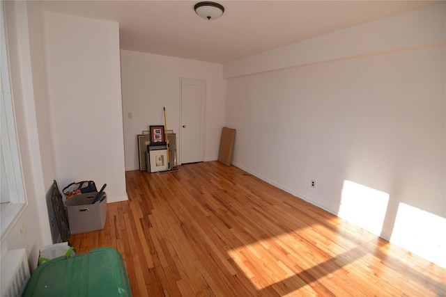 unfurnished room featuring a skylight, radiator heating unit, and light hardwood / wood-style floors