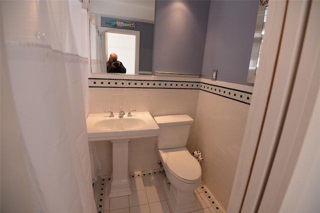 bathroom with tile patterned floors, tile walls, and toilet