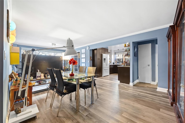 dining area with light hardwood / wood-style floors and ornamental molding