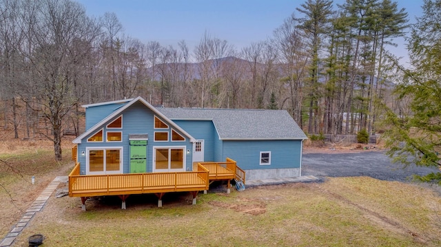 back of property featuring a deck with mountain view and a yard