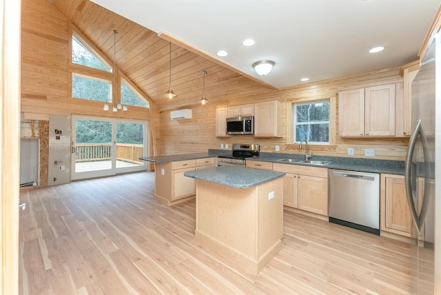 kitchen with pendant lighting, a center island, wood walls, sink, and appliances with stainless steel finishes