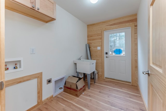 washroom with wood walls, cabinets, light hardwood / wood-style flooring, washer hookup, and hookup for an electric dryer