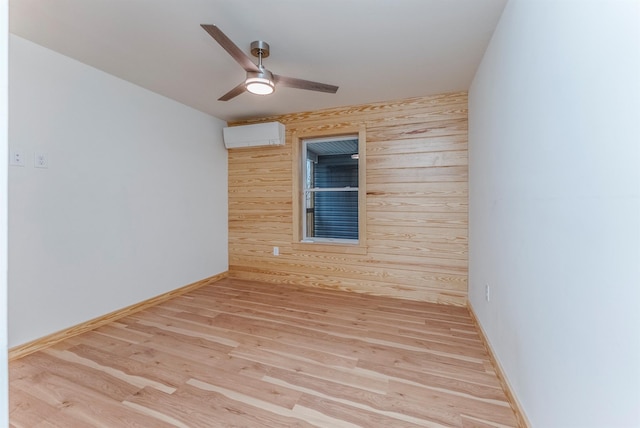 unfurnished room with a wall mounted AC, wood walls, ceiling fan, and light wood-type flooring