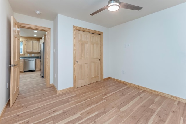 unfurnished bedroom featuring ceiling fan, stainless steel fridge, light wood-type flooring, and a closet