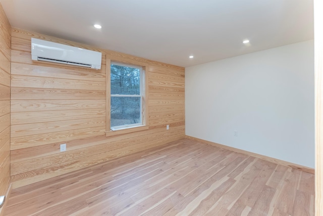 empty room featuring light hardwood / wood-style floors, an AC wall unit, and wooden walls