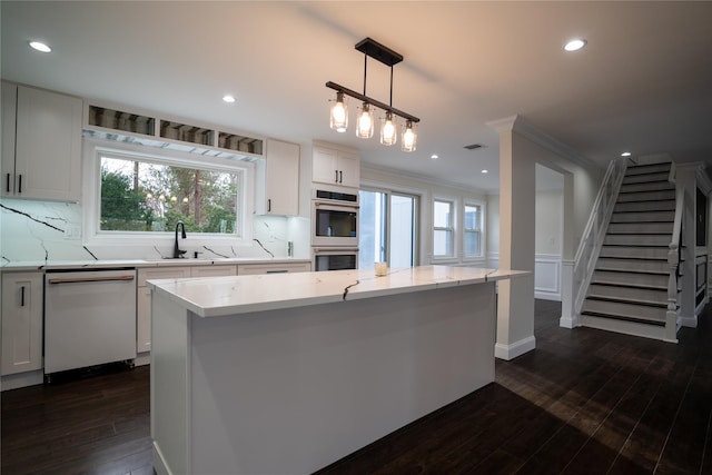 kitchen with light stone countertops, white dishwasher, pendant lighting, a center island, and white cabinetry