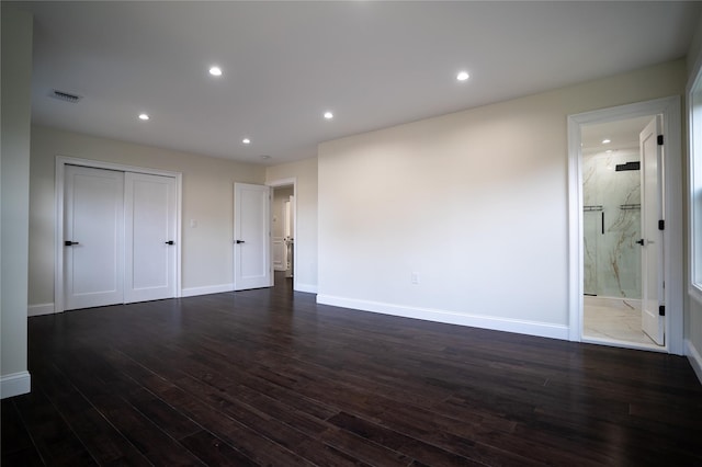 unfurnished bedroom featuring dark hardwood / wood-style floors, a closet, and ensuite bath