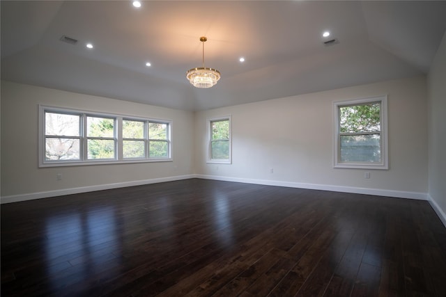 spare room featuring a chandelier, a healthy amount of sunlight, lofted ceiling, and dark wood-type flooring