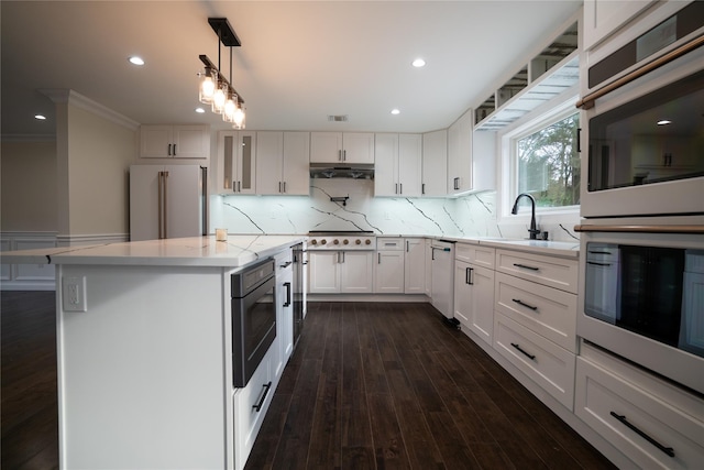 kitchen featuring pendant lighting, backsplash, sink, white cabinetry, and stainless steel appliances