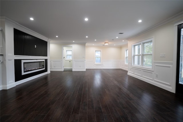 unfurnished living room featuring dark wood-type flooring, a healthy amount of sunlight, and ornamental molding