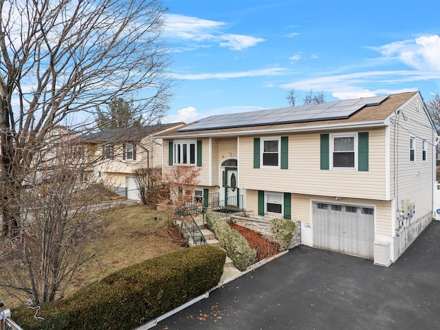 split foyer home featuring solar panels and a garage