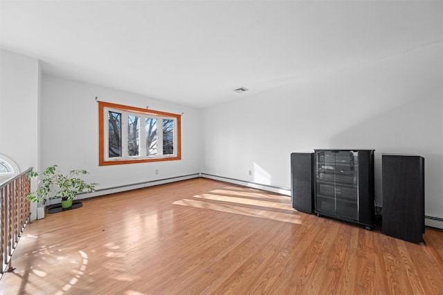 interior space with a baseboard heating unit and light hardwood / wood-style flooring