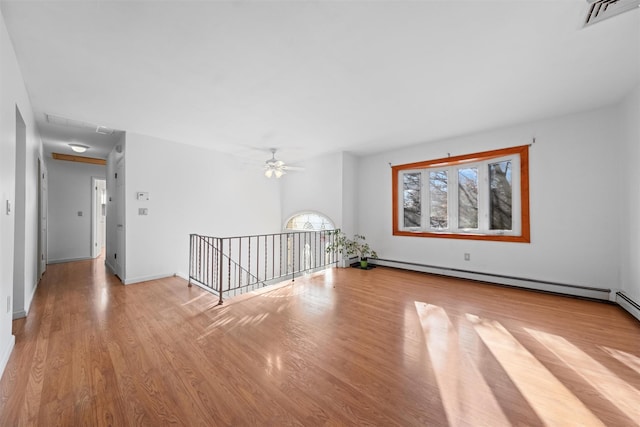 empty room featuring ceiling fan, light hardwood / wood-style floors, and baseboard heating