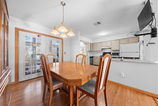 dining space with light hardwood / wood-style floors and a notable chandelier