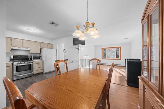 dining room featuring ceiling fan with notable chandelier and dark hardwood / wood-style floors