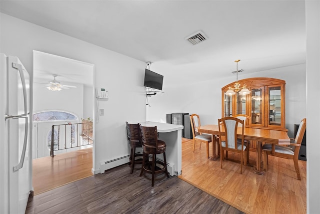 dining space featuring ceiling fan with notable chandelier and dark hardwood / wood-style flooring