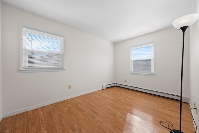 unfurnished room with light wood-type flooring and a baseboard heating unit