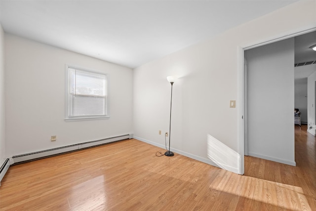 empty room featuring hardwood / wood-style floors and a baseboard radiator