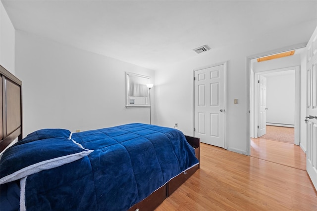 bedroom with wood-type flooring and baseboard heating