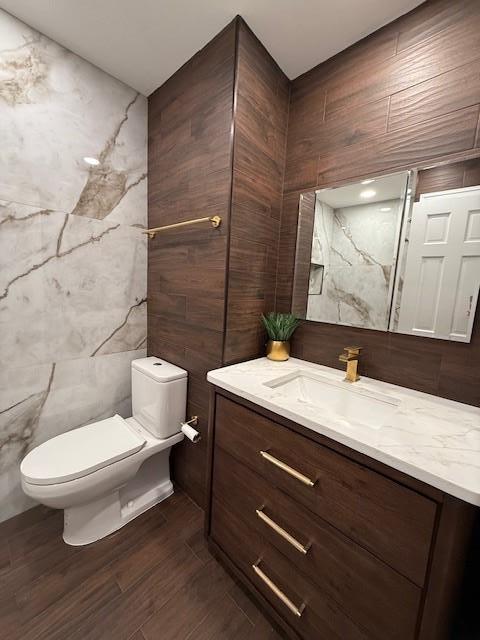 bathroom with vanity, toilet, and tile walls