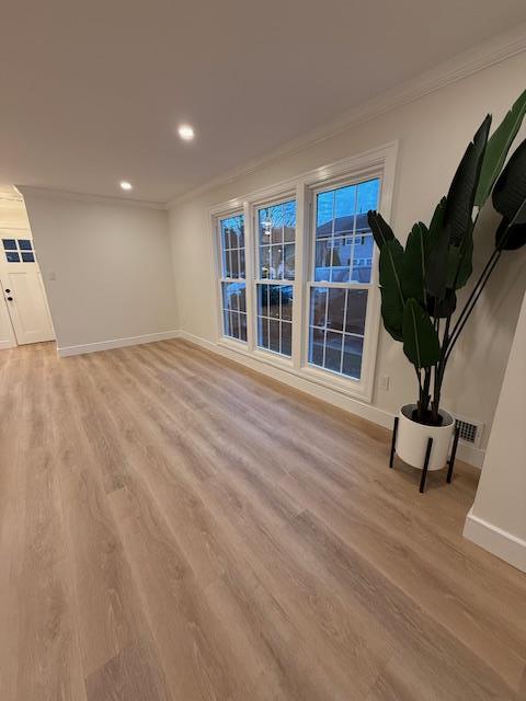 unfurnished living room with light wood-type flooring and ornamental molding