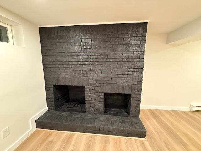 interior details with a fireplace, hardwood / wood-style floors, and a baseboard heating unit