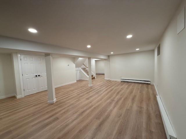 basement featuring light hardwood / wood-style flooring and a baseboard heating unit