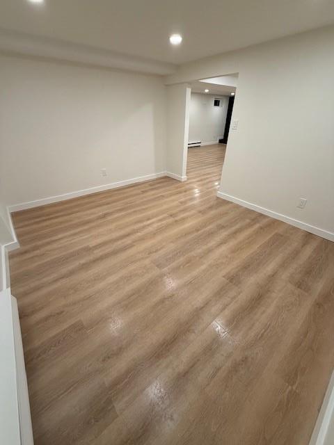 unfurnished room featuring baseboard heating and light hardwood / wood-style flooring