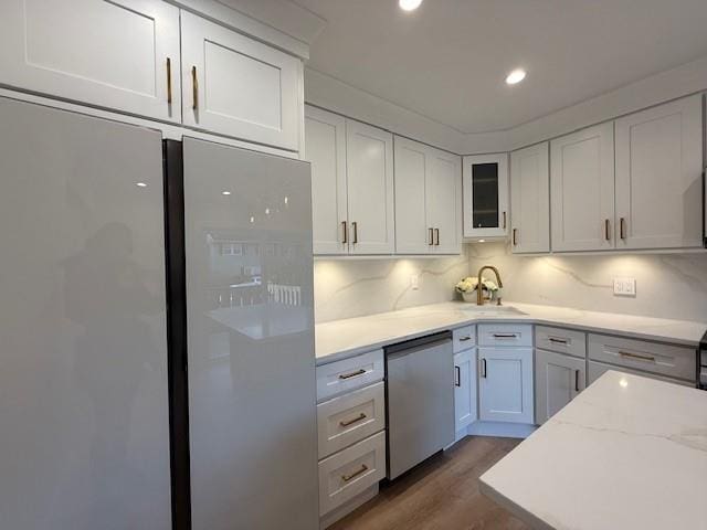 kitchen featuring refrigerator, sink, dishwasher, dark hardwood / wood-style floors, and white cabinetry