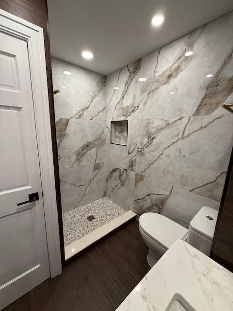 bathroom with toilet, wood-type flooring, walk in shower, and tile walls