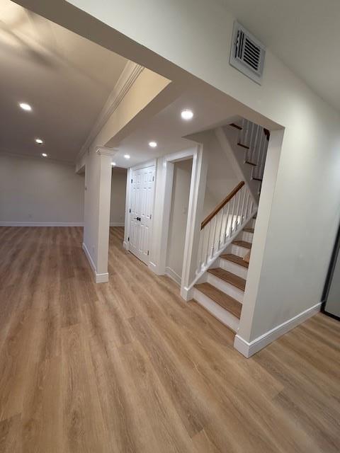 basement featuring crown molding and light hardwood / wood-style flooring